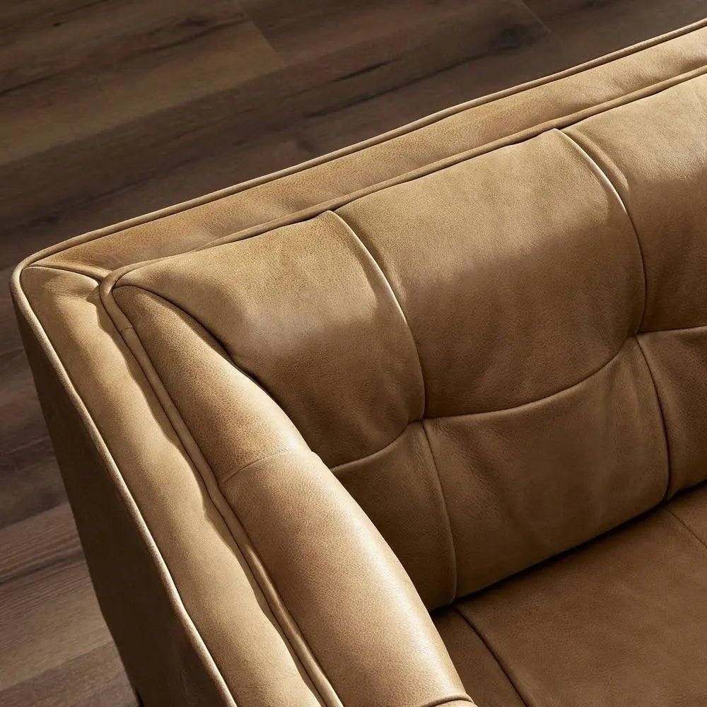 Close-up of a brown leather sofa with tufted design in modern living room.