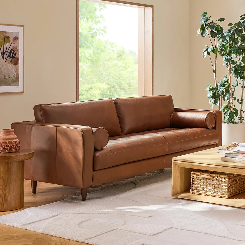 Brown leather sofa in a living room with a coffee table and decorative items.