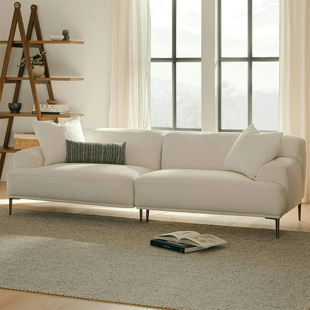 Beige sofa in a living room with pillows and stylish legs.