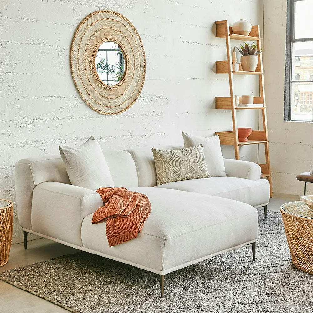 Modern living room with a white sofa, decorative pillows, and a wooden ladder shelf.