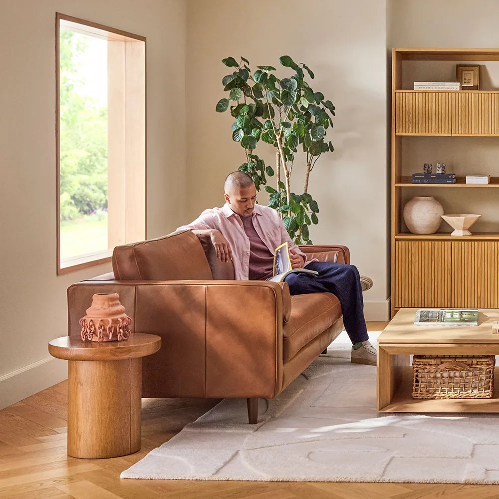 A brown leather sofa in a modern living room with a wooden table.