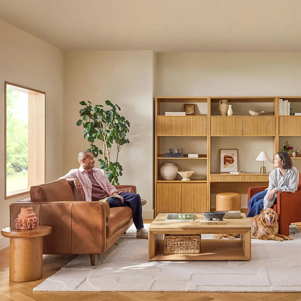 Living room with a stylish sectional sofa and a bookshelf in the background.