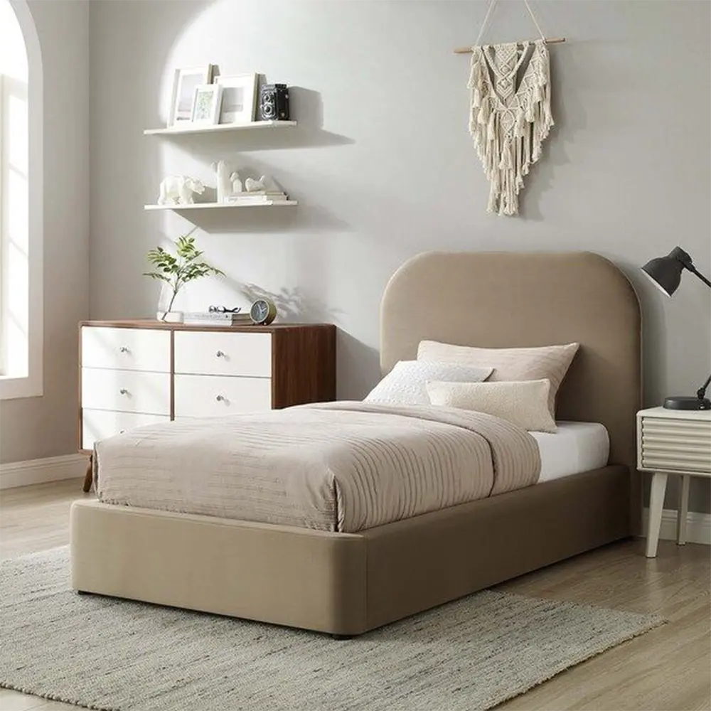 A low-profile platform bed with a tall, rounded headboard upholstered in a warm taupe fabric, styled with neutral bedding in a bright, modern bedroom.