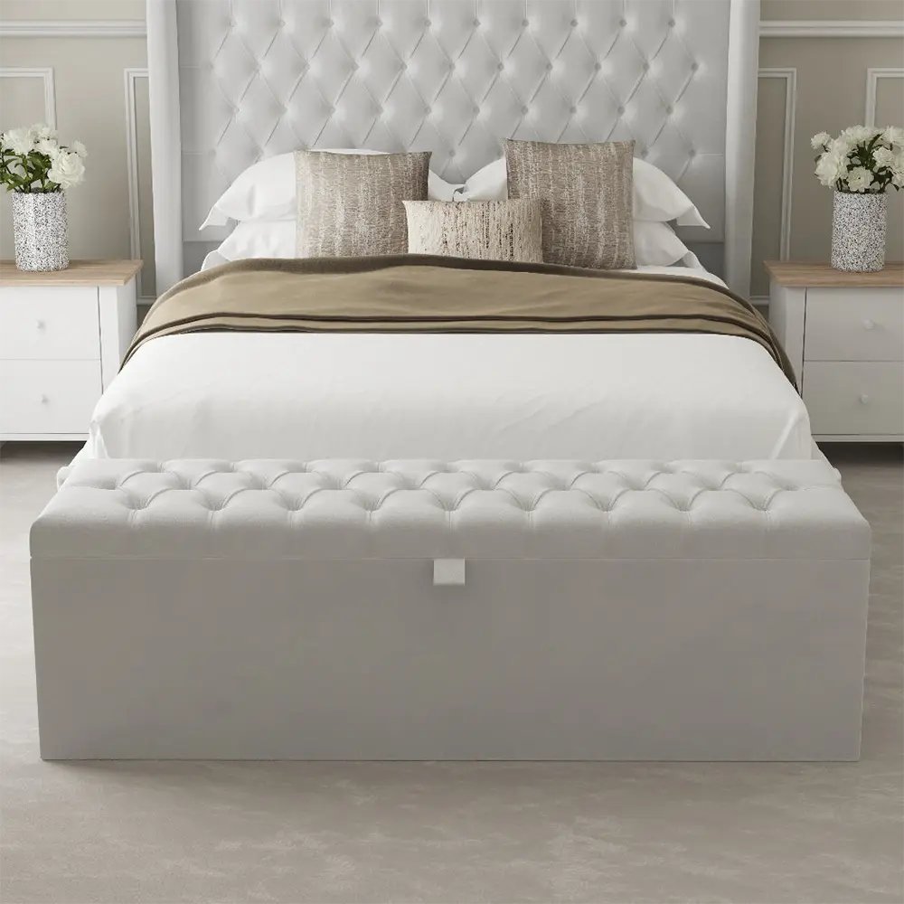 White upholstered ottoman with tufted design in a bedroom setting.