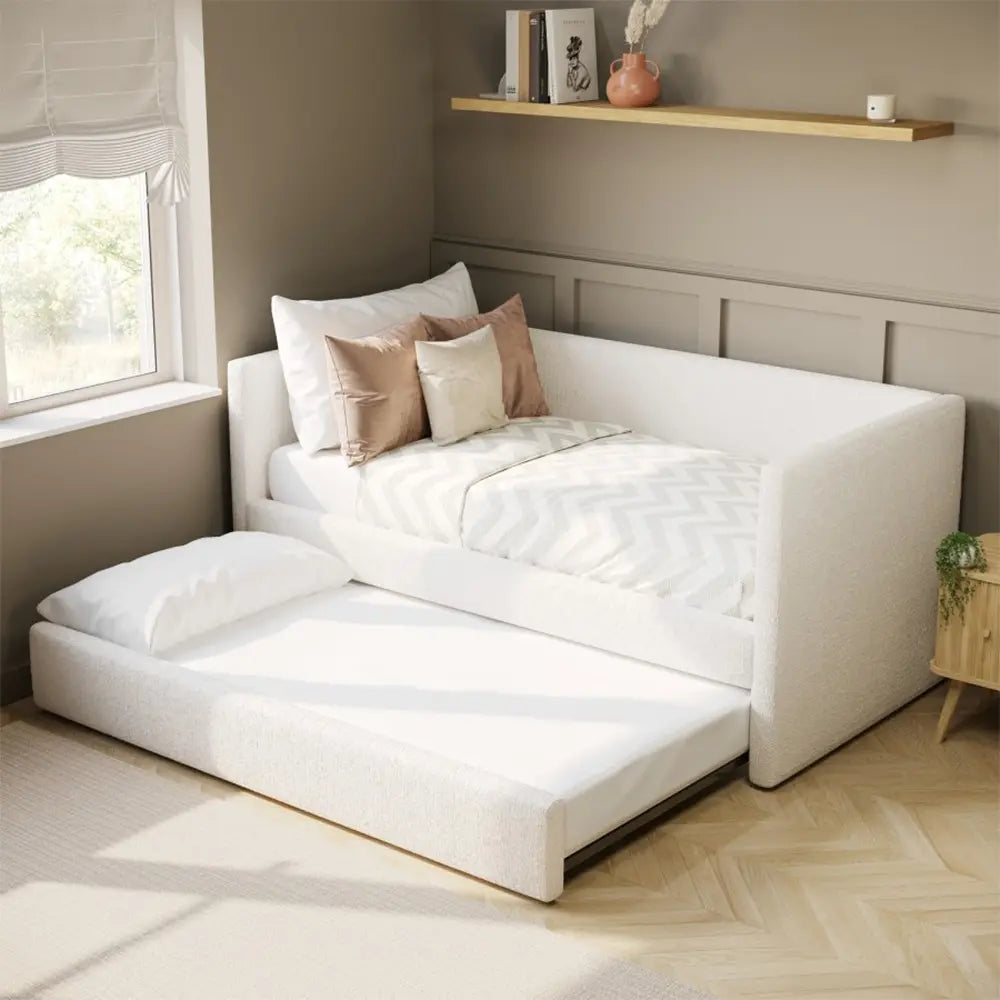 White sofa bed in a room with pillows and shelf.