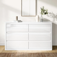 White dresser with decorative items in a room with a mirror and plant