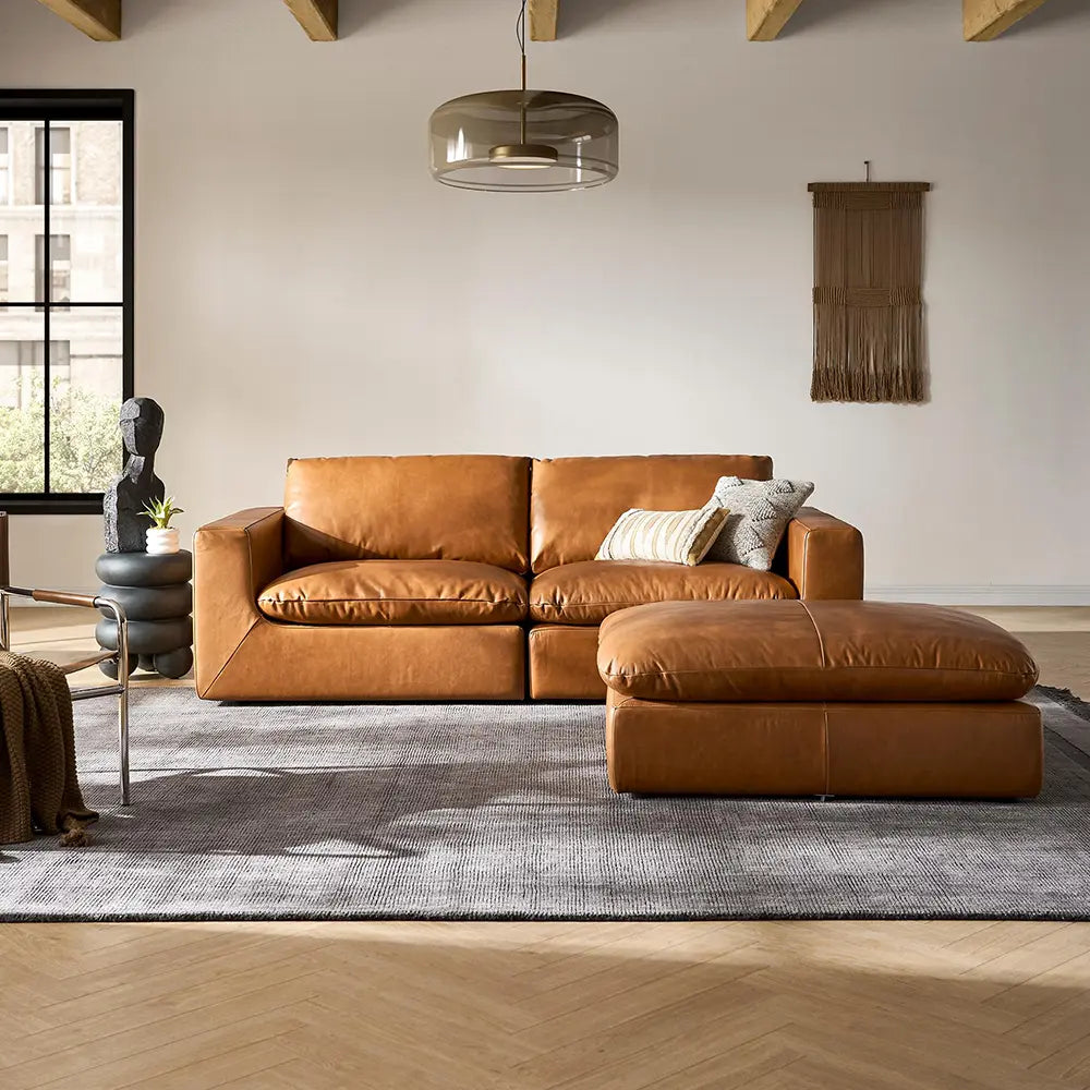 Brown leather sectional sofa in a modern living room with a rug and decorative items.