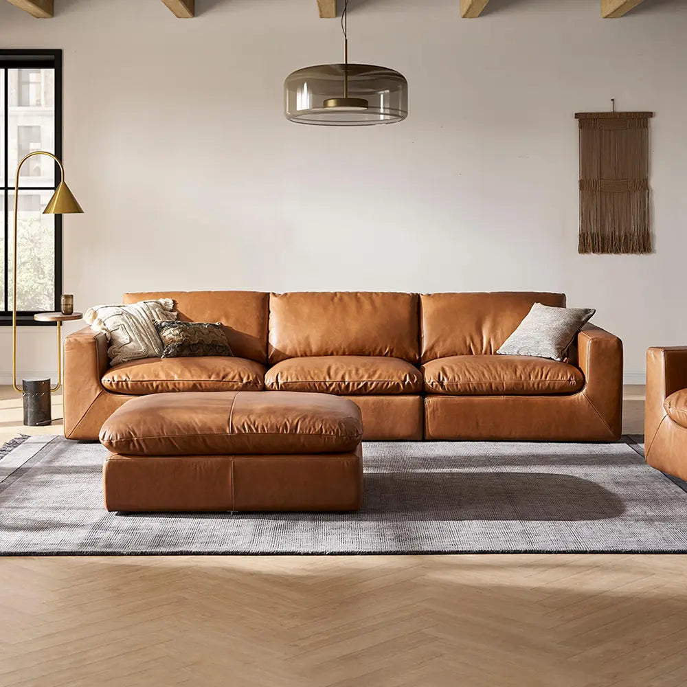Brown leather sofa in a modern living room with a rug and decorative pillows.