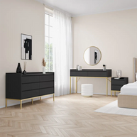 Modern bedroom with black dresser, vanity table, and white bed.