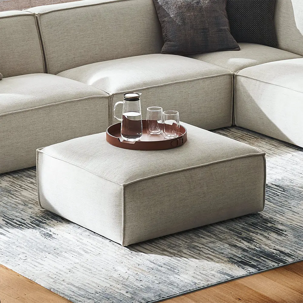 Beige sectional sofa with a matching ottoman in modern lounge.