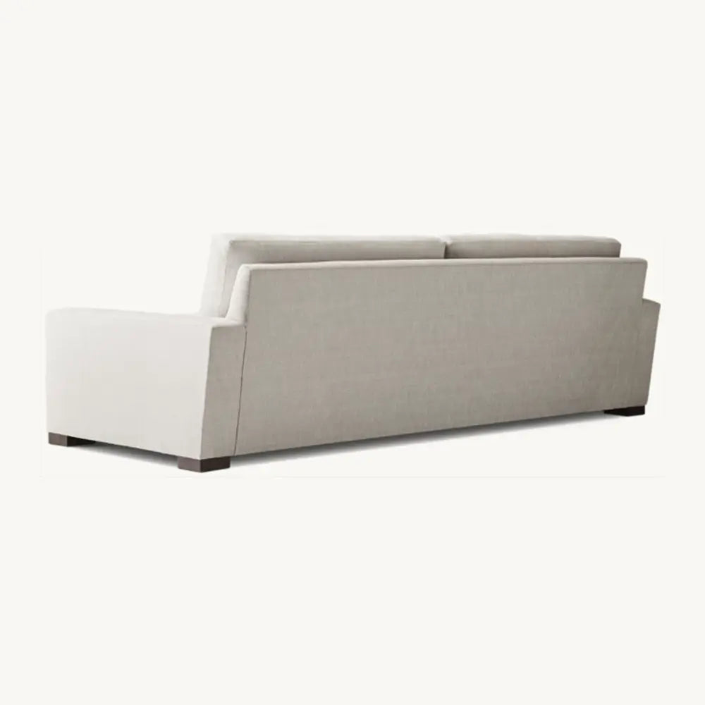 Off-white sofa from backside with sleek profile in lounge setting.