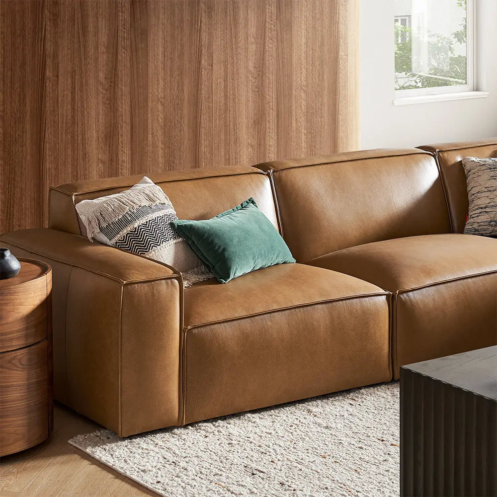 Brown leather sofa with decorative pillows in a living room setting.