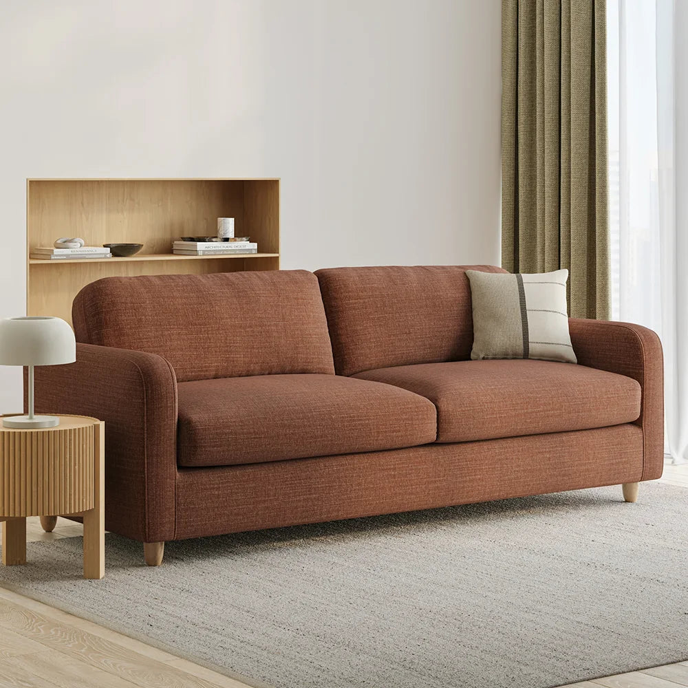 Brown sofa in a living room with a side table and a book shelf.