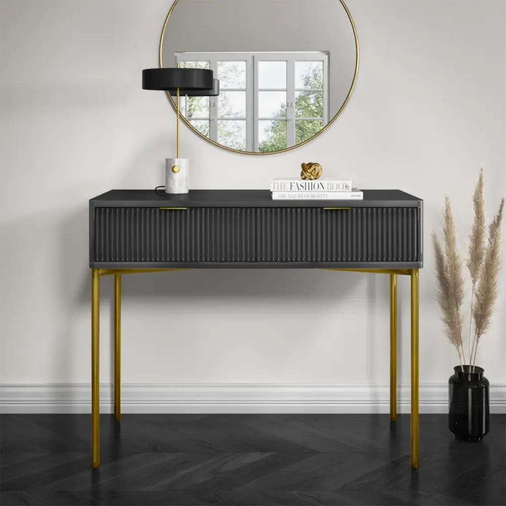 Console table with gold legs and black top in a room setting.