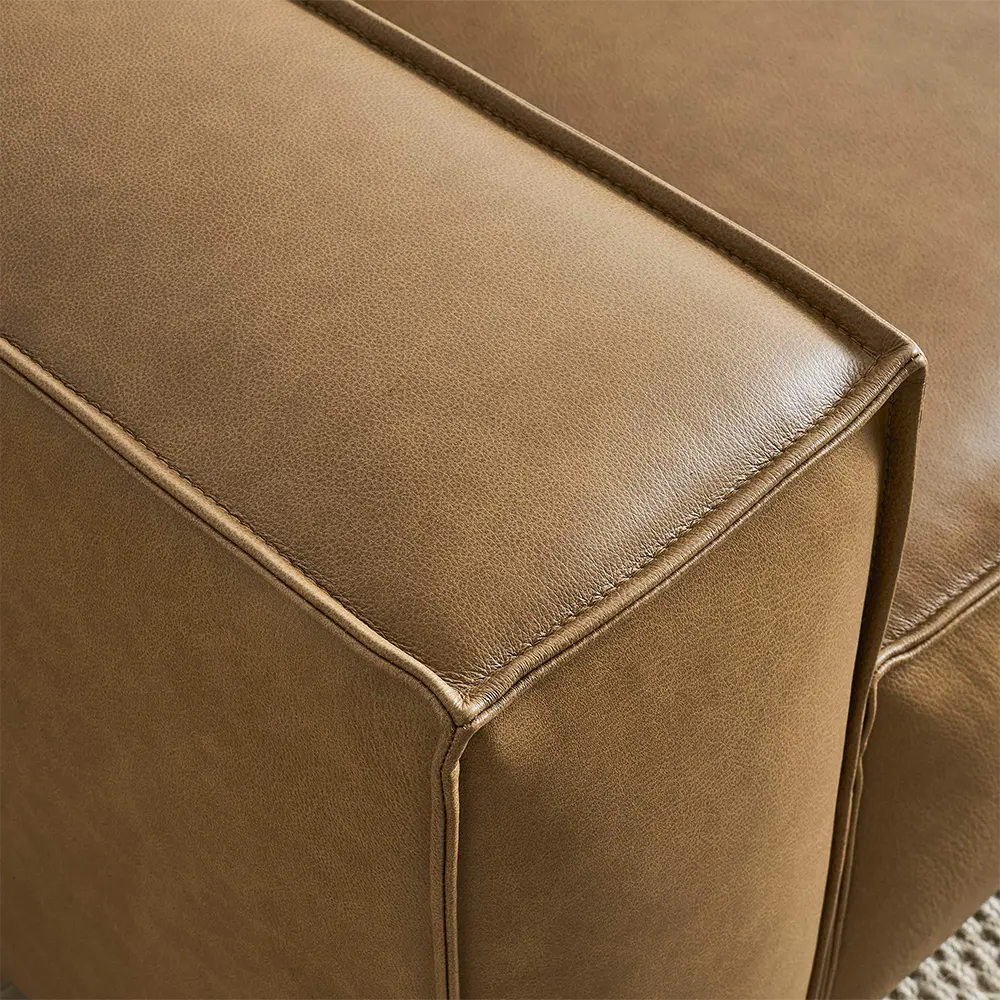 Close-up of a brown leather corner sectional sofa in lounge.