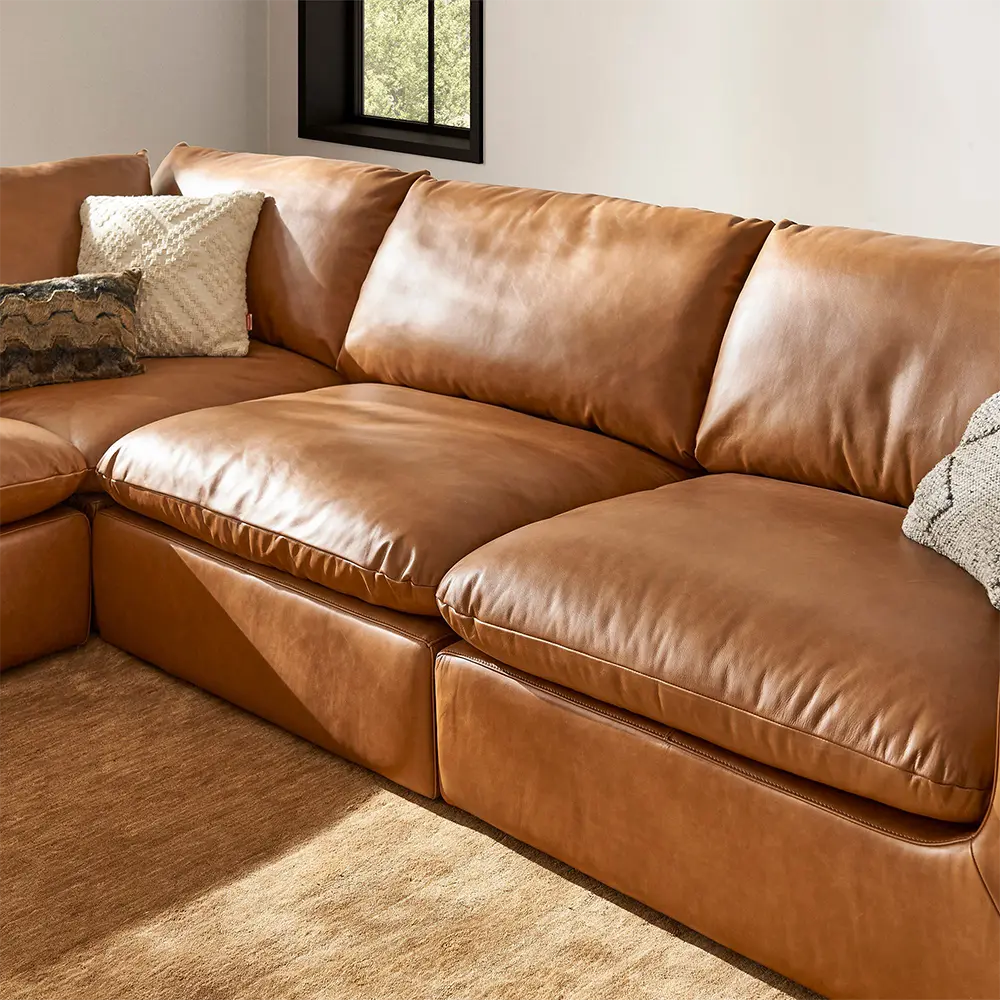 Brown leather sectional sofa with cushions in a living room.