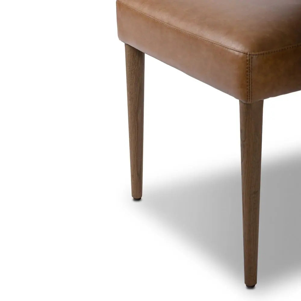 Brown leather chair with wooden legs.