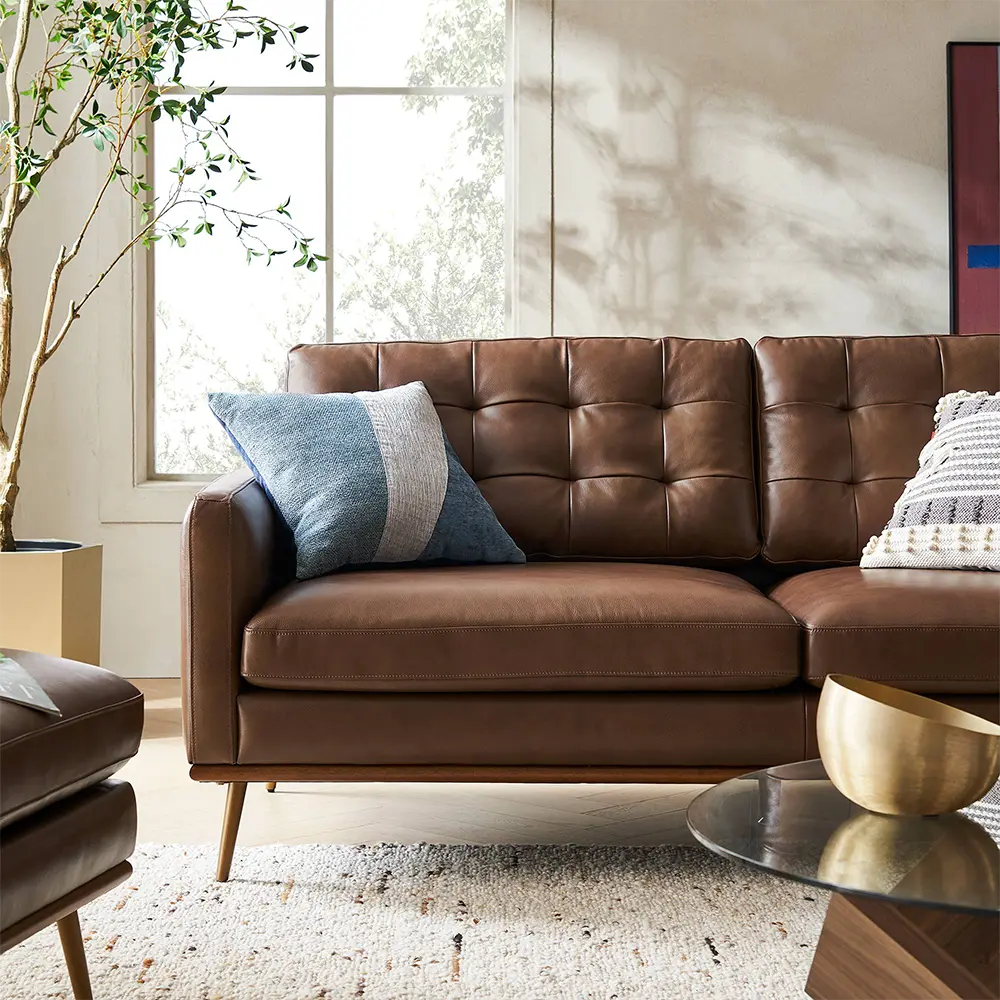 Brown leather sofa with decorative pillows in a living room setting.