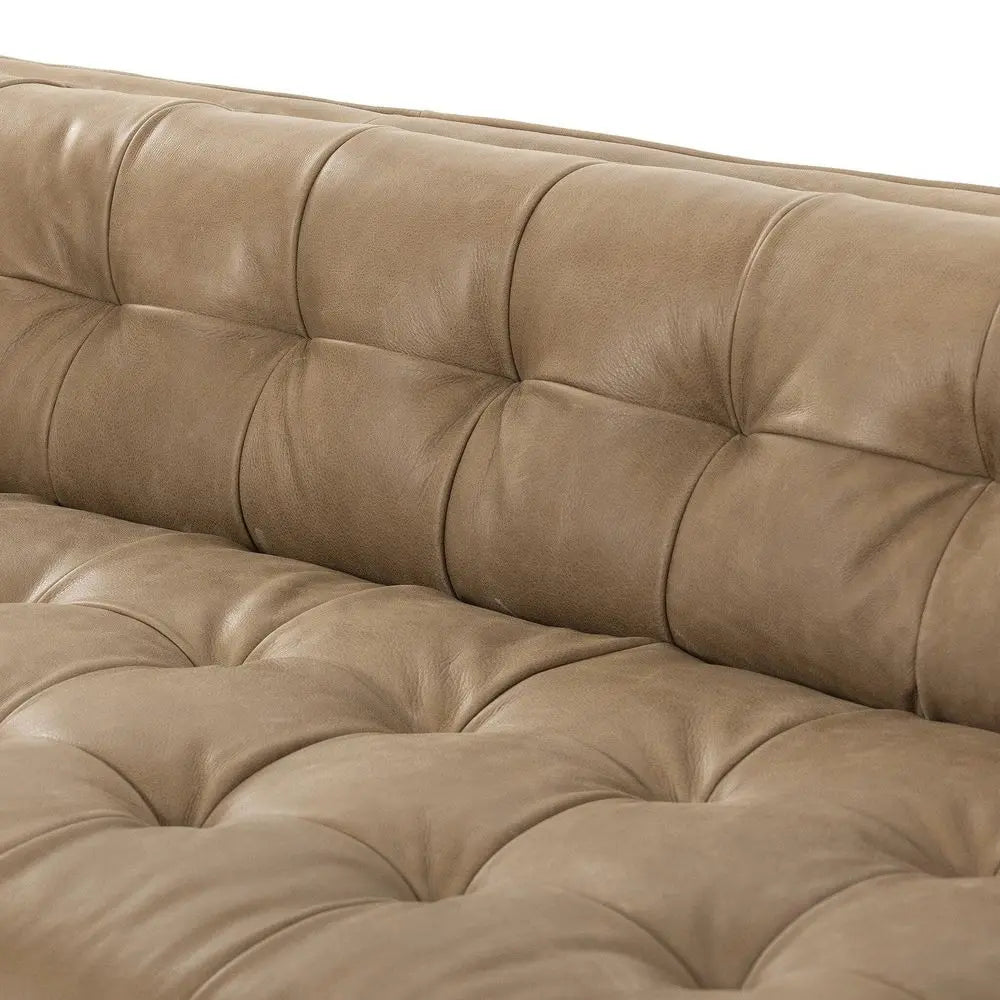 Close-up of a brown leather sofa with tufted design.